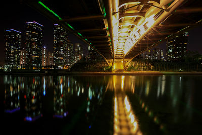 Illuminated bridge over river and buildings at night