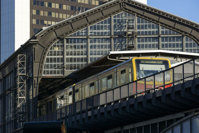 Low angle view of s-bahn train on bridge against buildings