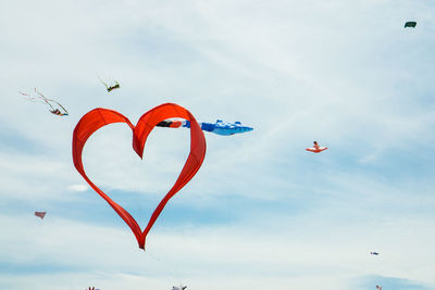 Low angle view of kites flying against sky