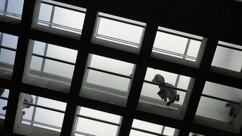 Low angle view of man working on glass window of building