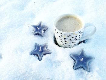 High angle view of coffee with star shaped candles on snow during christmas