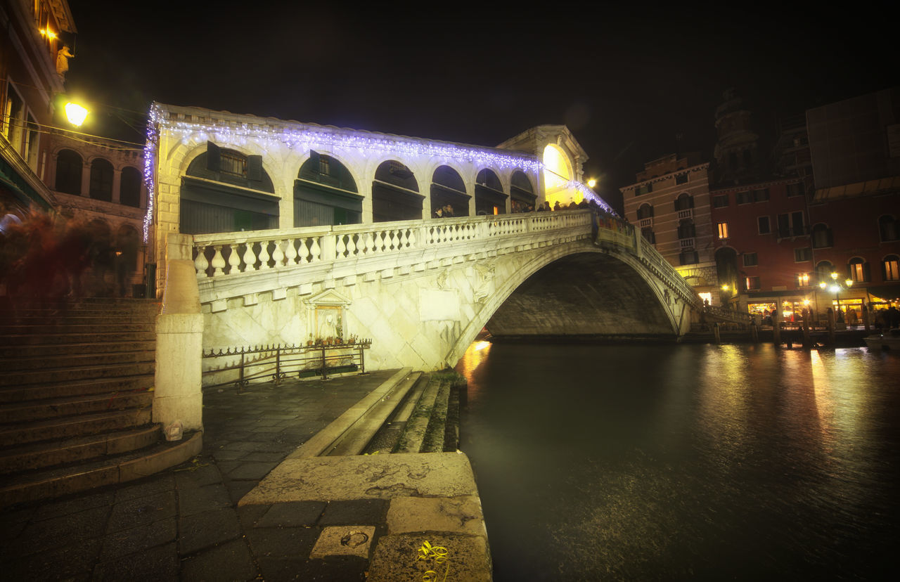 ILLUMINATED BRIDGE OVER RIVER AT NIGHT