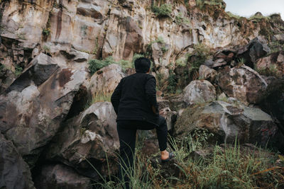 Rear view of man sitting on rock