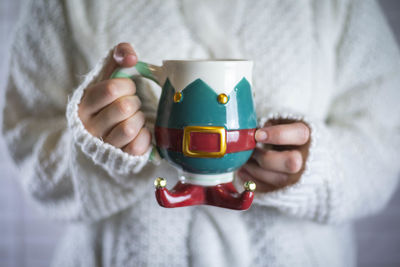 Midsection of woman holding hot drink in an elf mug