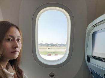 Portrait of woman sitting by window in airplane