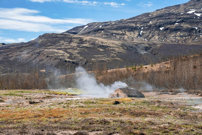 Scenic view of geothermal smoking field at smidur geyser valley against mountain