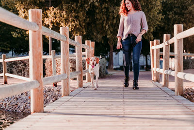 Woman with dog standing on footbridge