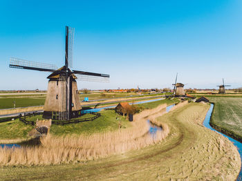 Traditional windmill on field against clear blue sky