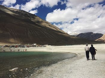 Rear view of women on landscape against cloudy sky