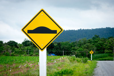 Road sign on field against sky