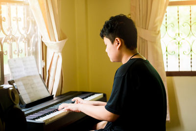 Side view of young man sitting at home