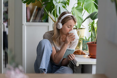 Woman looking away while sitting on table at home