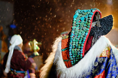 Close-up of traditional clothing with man sitting in background during snowfall at night