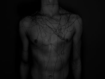 Midsection of man with threads against black background