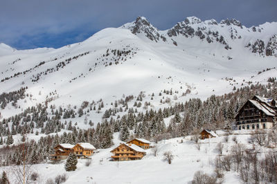 Scenic view of snow covered houses and mountains against sky