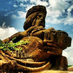 Low angle view of rock formation against cloudy sky