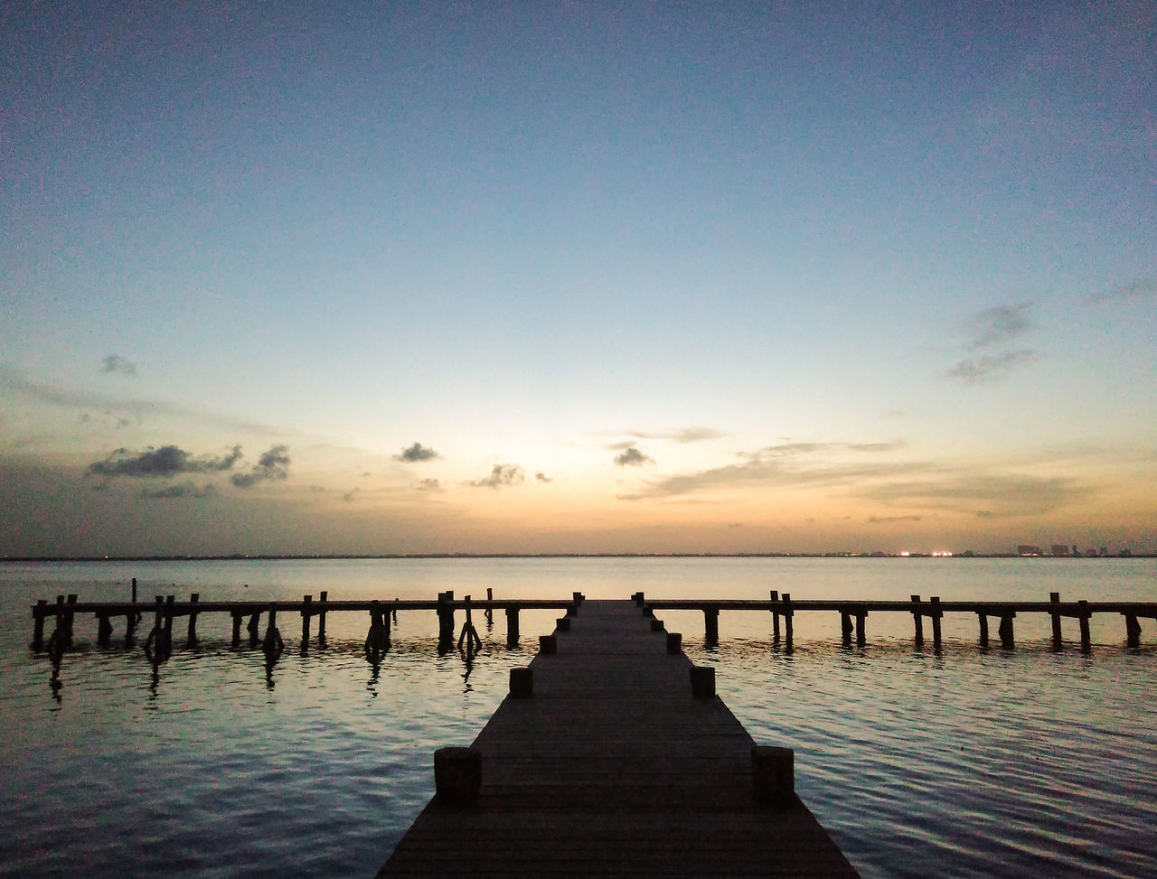 sea, pier, jetty, water, sunset, tranquil scene, tranquility, nature, beauty in nature, idyllic, freedom, silhouette, scenics, beach, wood paneling, outdoors, clear sky, sky, horizon over water, no people