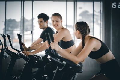 Friends exercising on exercise bikes in gym
