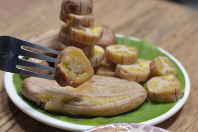 Grilled banana with dipping sauce on wooden table.