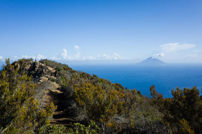 Scenic view of sea and mountains against blue sky