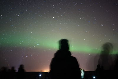 Silhouette people looking at star field against sky at night