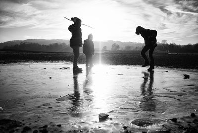 Silhouette men standing on beach against sky