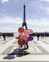 People with balloons standing in front of eiffel tower