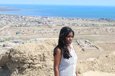 Portrait of beautiful woman standing on land against sea