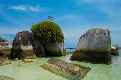 Rock formation on beach against blue sky