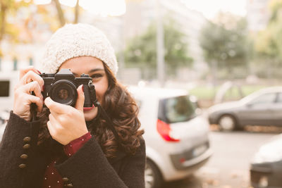 Portrait of young woman photographing with camera