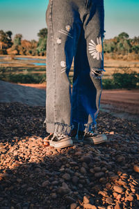 Low section of man standing on pebbles