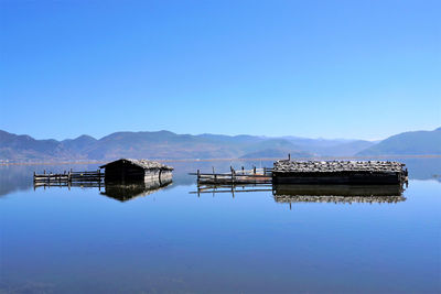 Pier on lake against clear blue sky