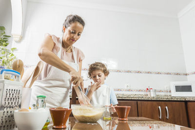 Mother and daughter standing in kitchen at home