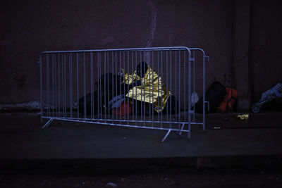 Homeless person wrapped in blanket sitting behind barricade on sidewalk