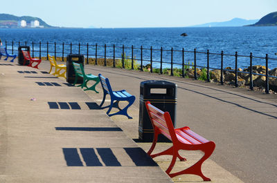 Colorful benches on footpath by sea