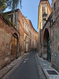 Empty road amidst buildings against clear sky