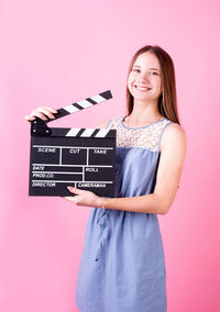 Portrait of smiling young woman against gray background