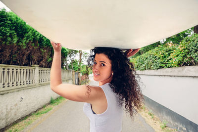 Portrait of young woman carrying surfboard on road