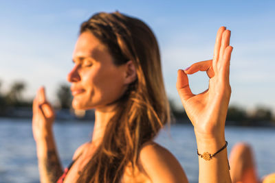 Young woman in deep concentration and mediation on a river bank