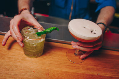 Midsection of woman holding drink on table