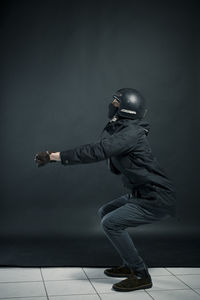 Side view of young man standing against wall