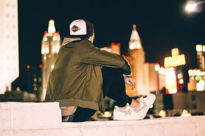 Rear view of person standing against illuminated city at night