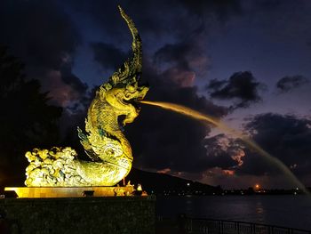 Statue by sea against sky at night