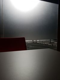 Illuminated electric lamp on table by window against sky