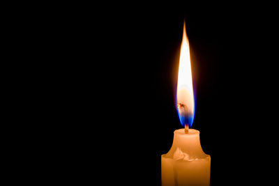 Close-up of lit candle in darkroom