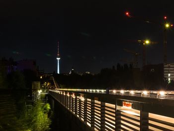 Illuminated bridge in city against sky at night