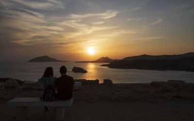 People at beach against sky during sunset