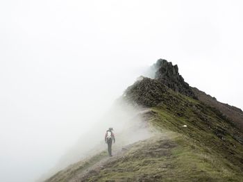 Rear view of hiker on mountain during foggy weather