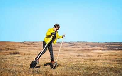 Young man walking on shovels in the field