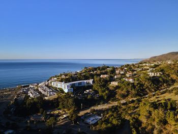 Scenic view of sea by buildings against clear blue sky